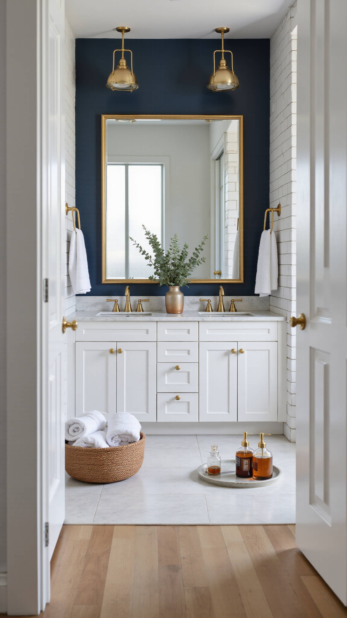 Modern luxury bathroom with gold-accented double vanity, Carrara marble top, navy accent wall, and geometric gold pendant lights, bathed in early morning sunlight.